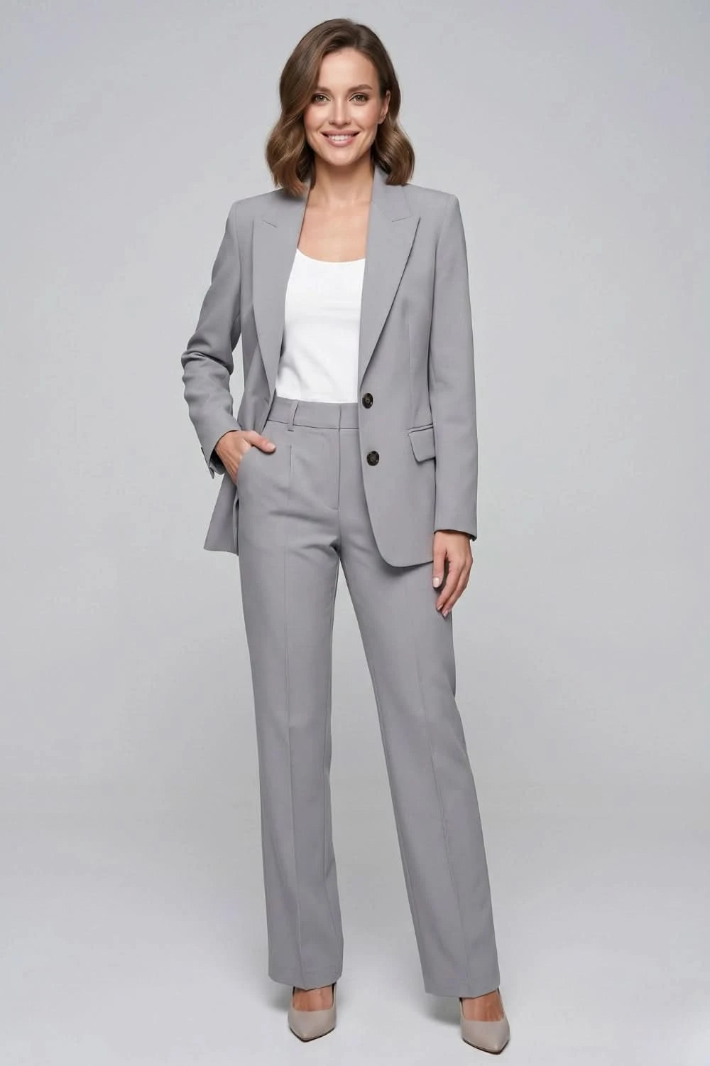 Woman wearing a gray suit with a white top on a gray background