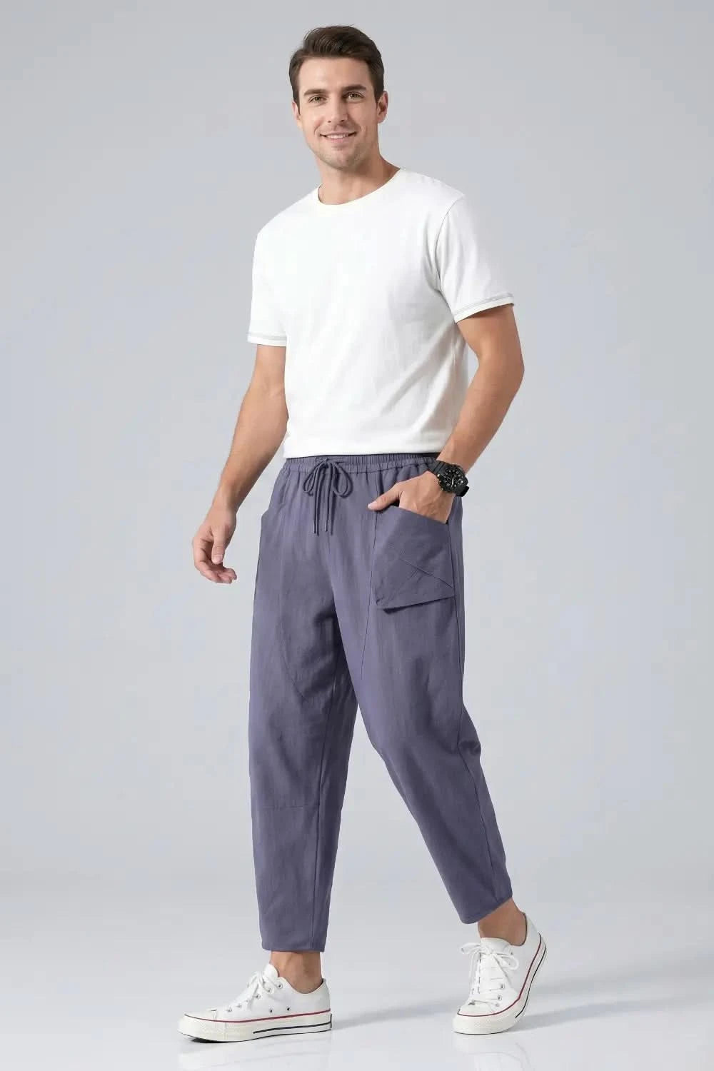 Man wearing a white t-shirt and gray pants on a light gray background