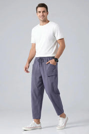 Man wearing a white t-shirt and gray pants on a light gray background