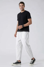 Man wearing a black t-shirt and white pants on a white background