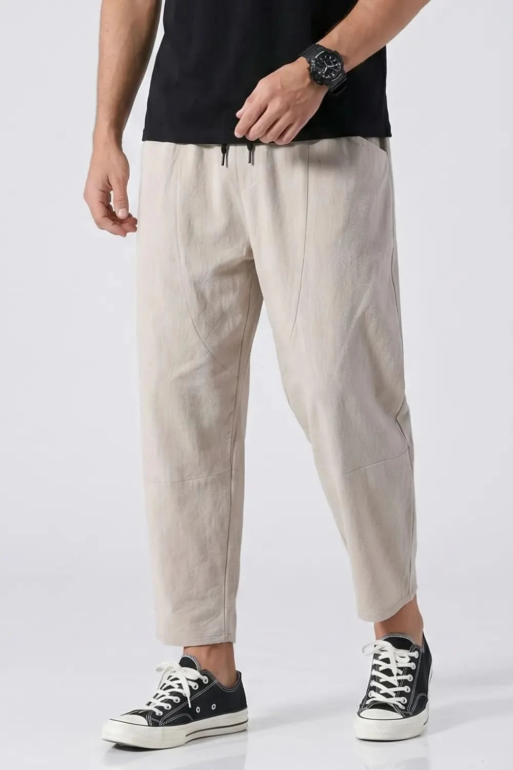 Person wearing beige pants and black sneakers on a white background
