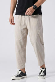 Person wearing beige pants and black sneakers on a white background
