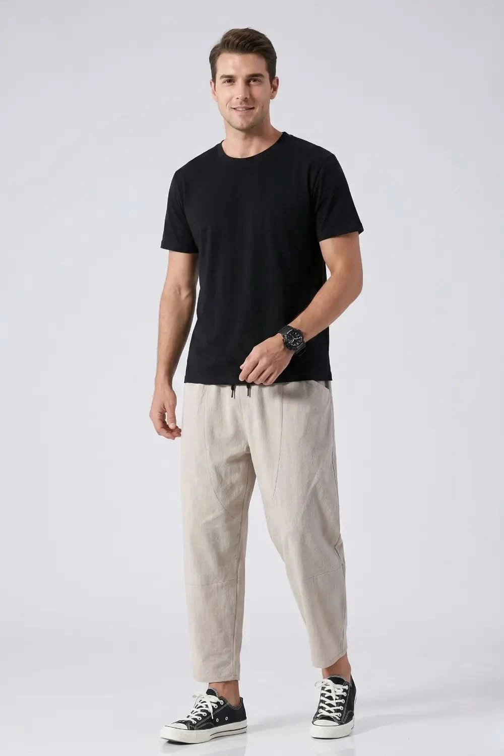Man wearing a black t-shirt and beige pants on a white background