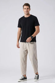 Man wearing a black t-shirt and beige pants on a white background