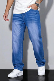 Person wearing blue jeans and white sneakers on a gray background