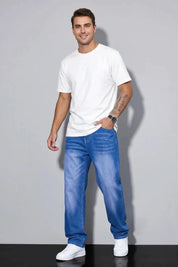 Man wearing a white t-shirt and blue jeans against a gray background