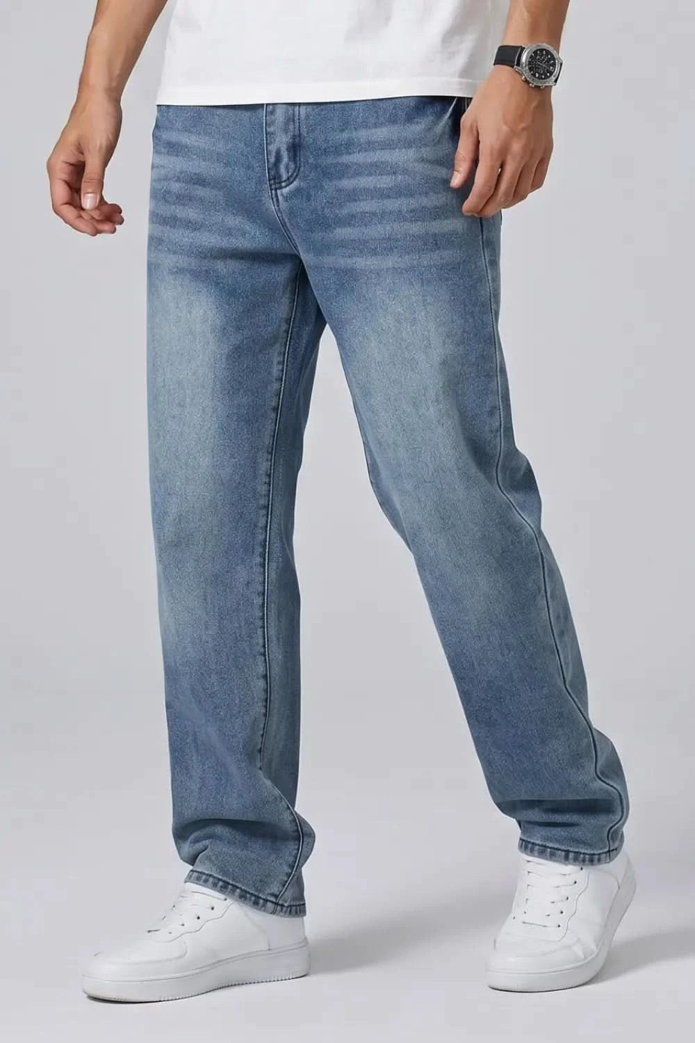 Person wearing blue jeans and white sneakers on a plain background