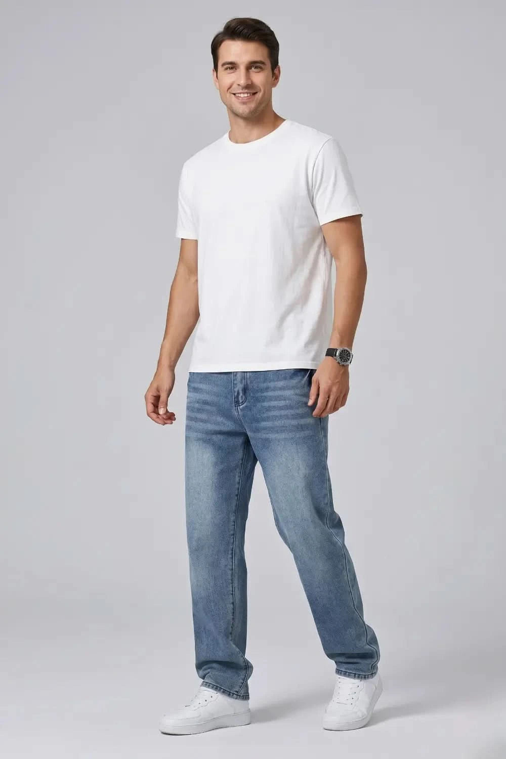 Man wearing a white t-shirt and blue jeans on a gray background