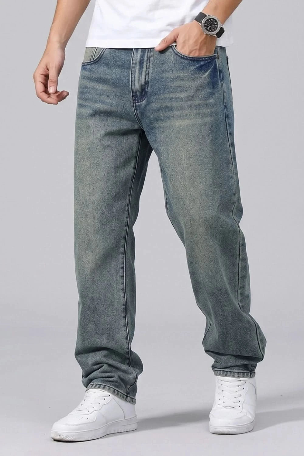 Person wearing blue jeans and white sneakers on a gray background