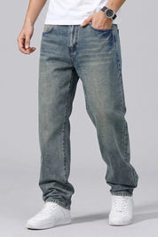 Person wearing blue jeans and white sneakers on a gray background