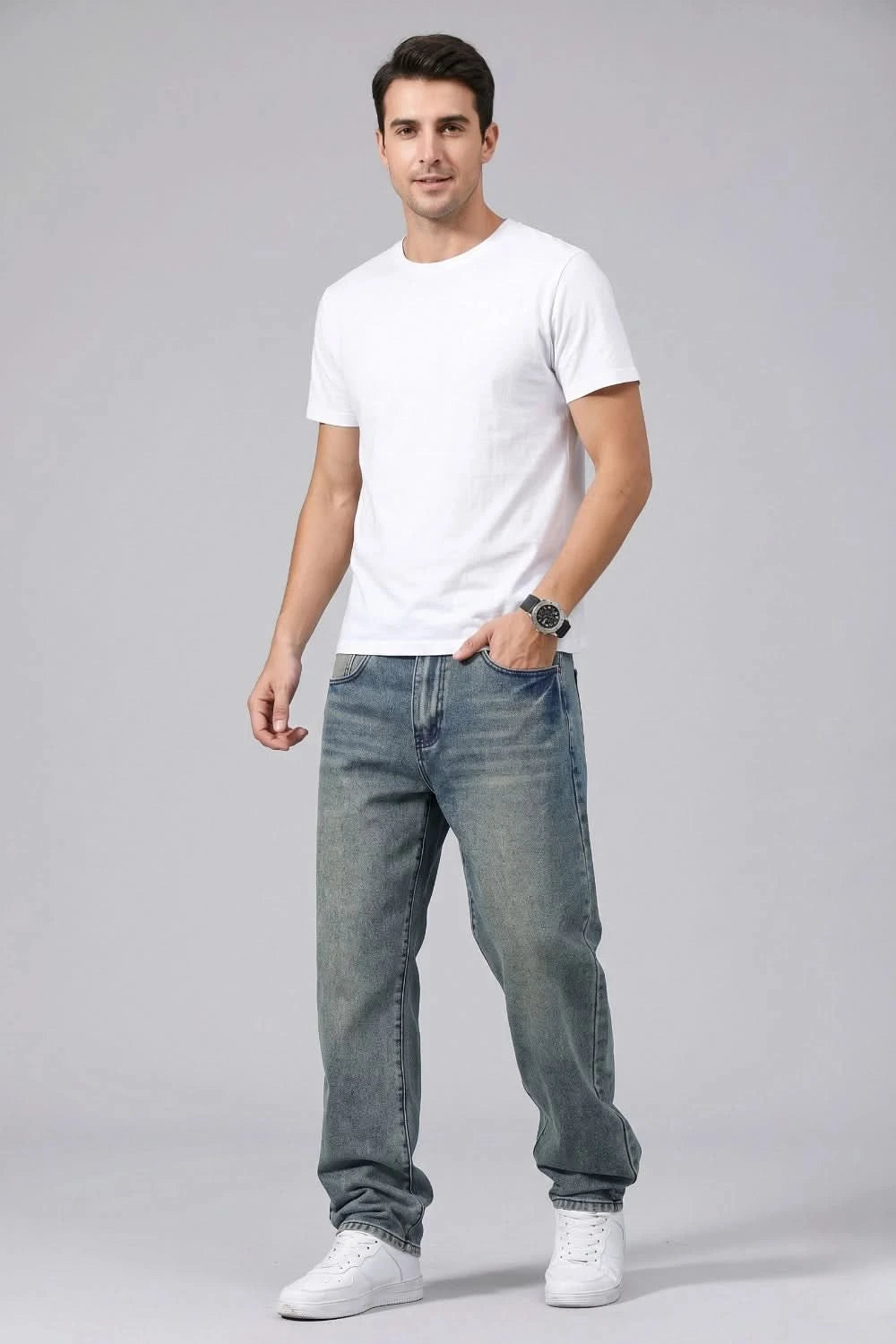 Man wearing a white t-shirt and blue jeans on a gray background