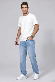 Man wearing a white t-shirt and light blue jeans on a gray background