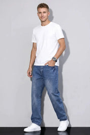 Man wearing a white t-shirt and blue jeans against a plain background
