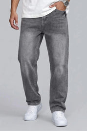 Person wearing gray jeans and white sneakers on a plain background