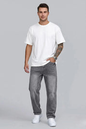 Man wearing a white t-shirt and gray jeans on a gray background