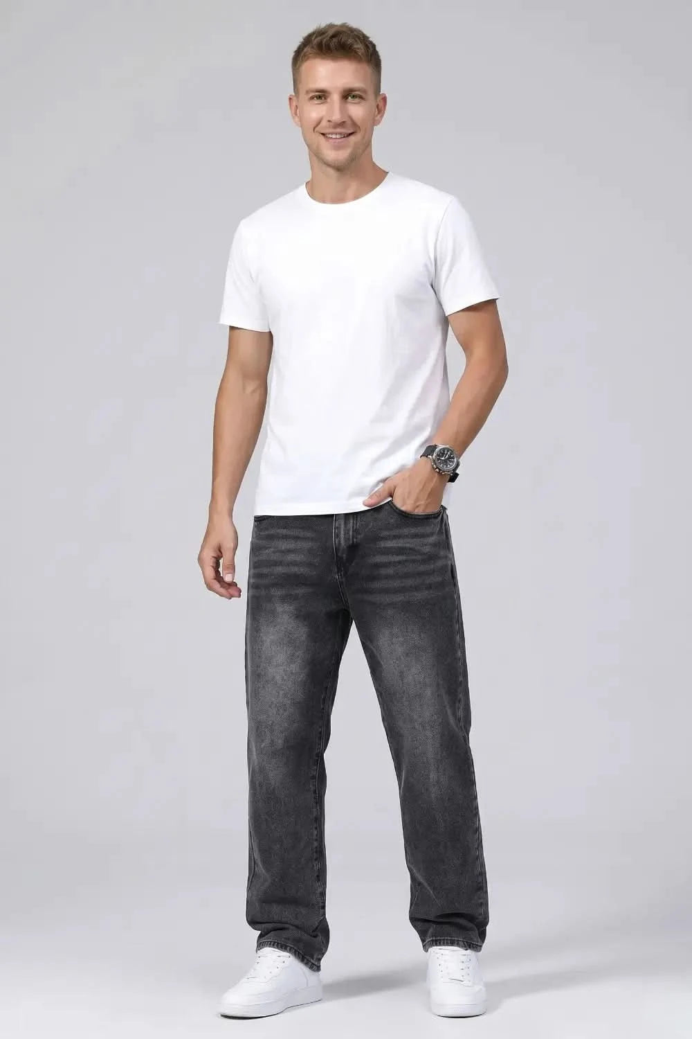 Man wearing a white t-shirt and black jeans on a gray background