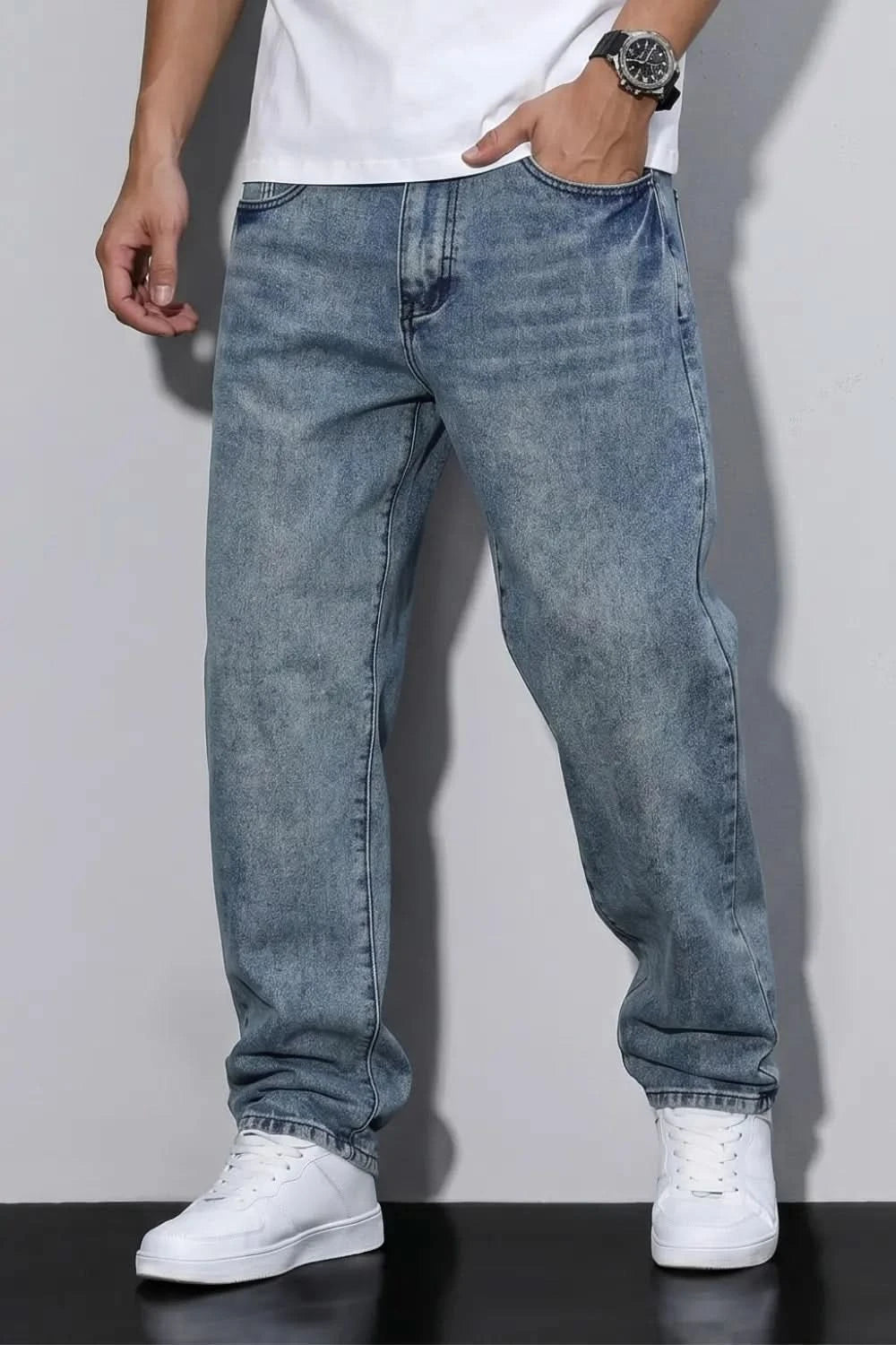 Person wearing blue jeans and white sneakers on a plain background