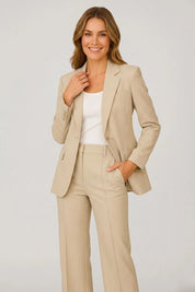 Woman wearing a beige suit with a white top on a light gray background