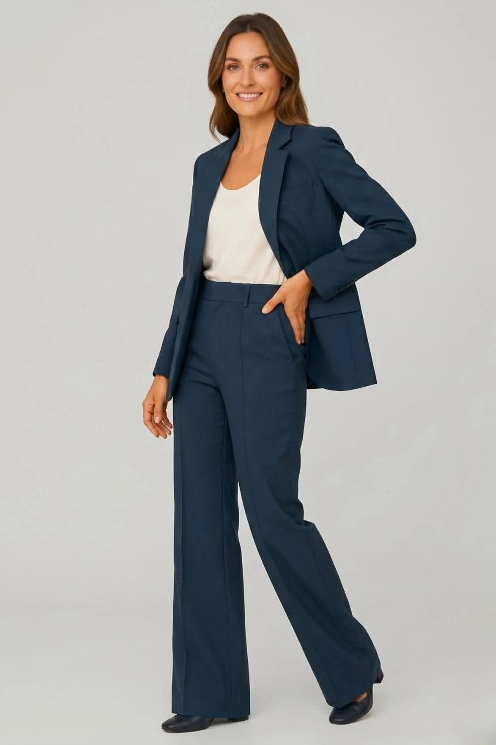 Woman wearing a navy blue suit with a white top on a gray background