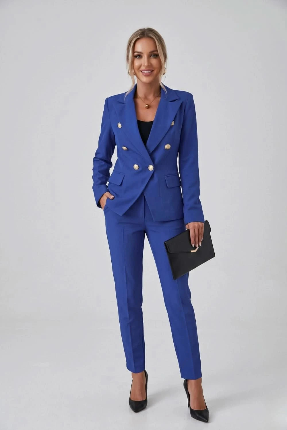 Woman wearing a blue suit with a black clutch against a white background