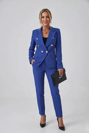 Woman wearing a blue suit with a black clutch against a white background