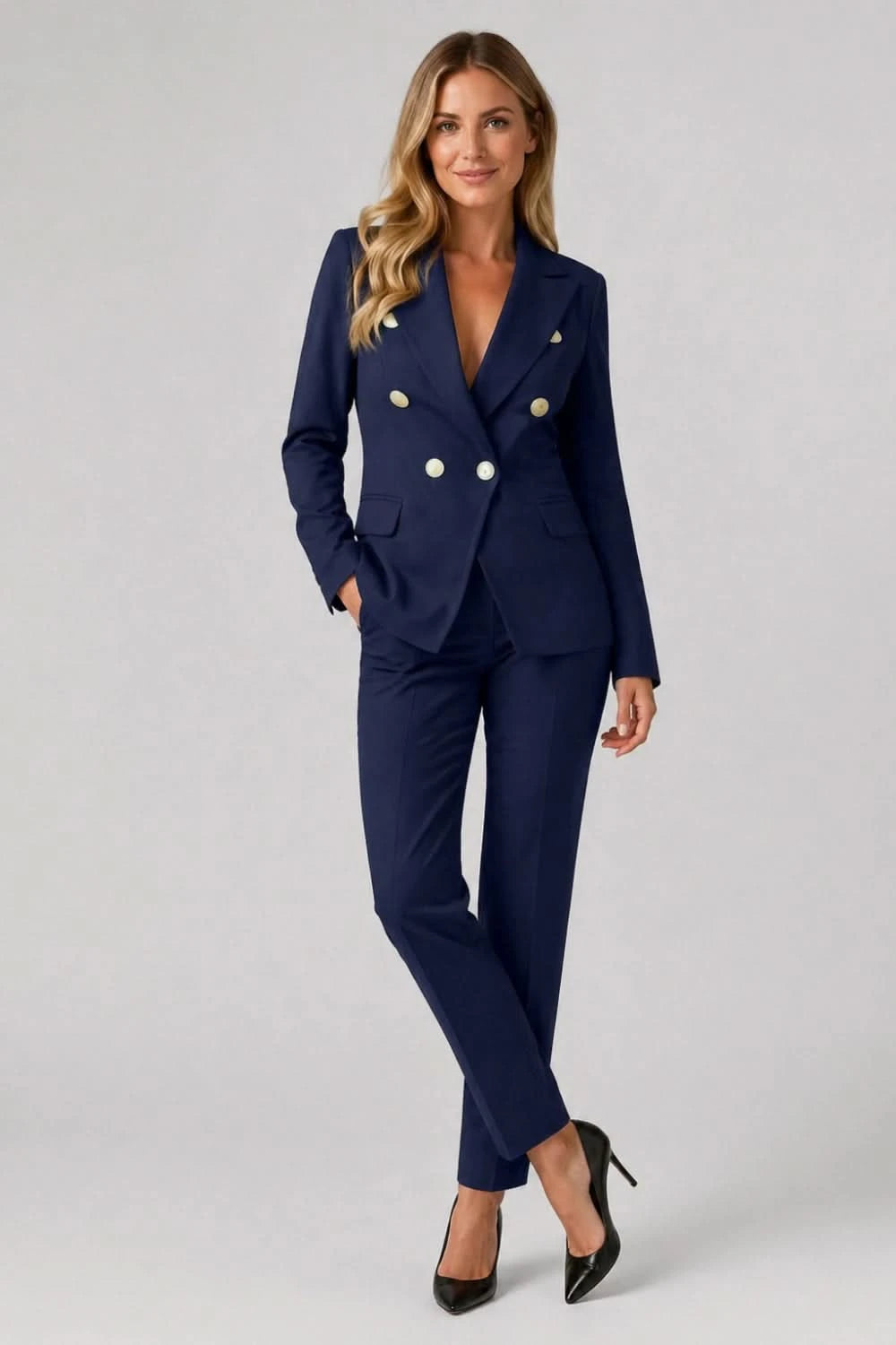 Woman wearing a navy blue suit with gold buttons on a gray background