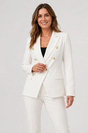 Woman wearing a white suit with gold buttons on a plain background