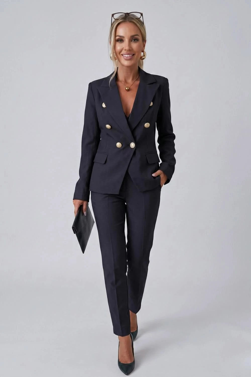 Woman wearing a navy blue suit with gold buttons on a gray background