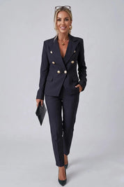 Woman wearing a navy blue suit with gold buttons on a gray background