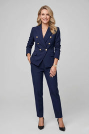 Woman wearing a navy blue suit with gold buttons on a gray background