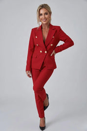 Woman wearing a red suit with gold buttons on a gray background