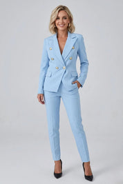 Woman wearing a light blue suit with gold buttons on a gray background