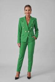 Woman wearing a green suit with gold buttons on a gray background