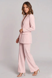 Woman wearing a pink suit on a gray background