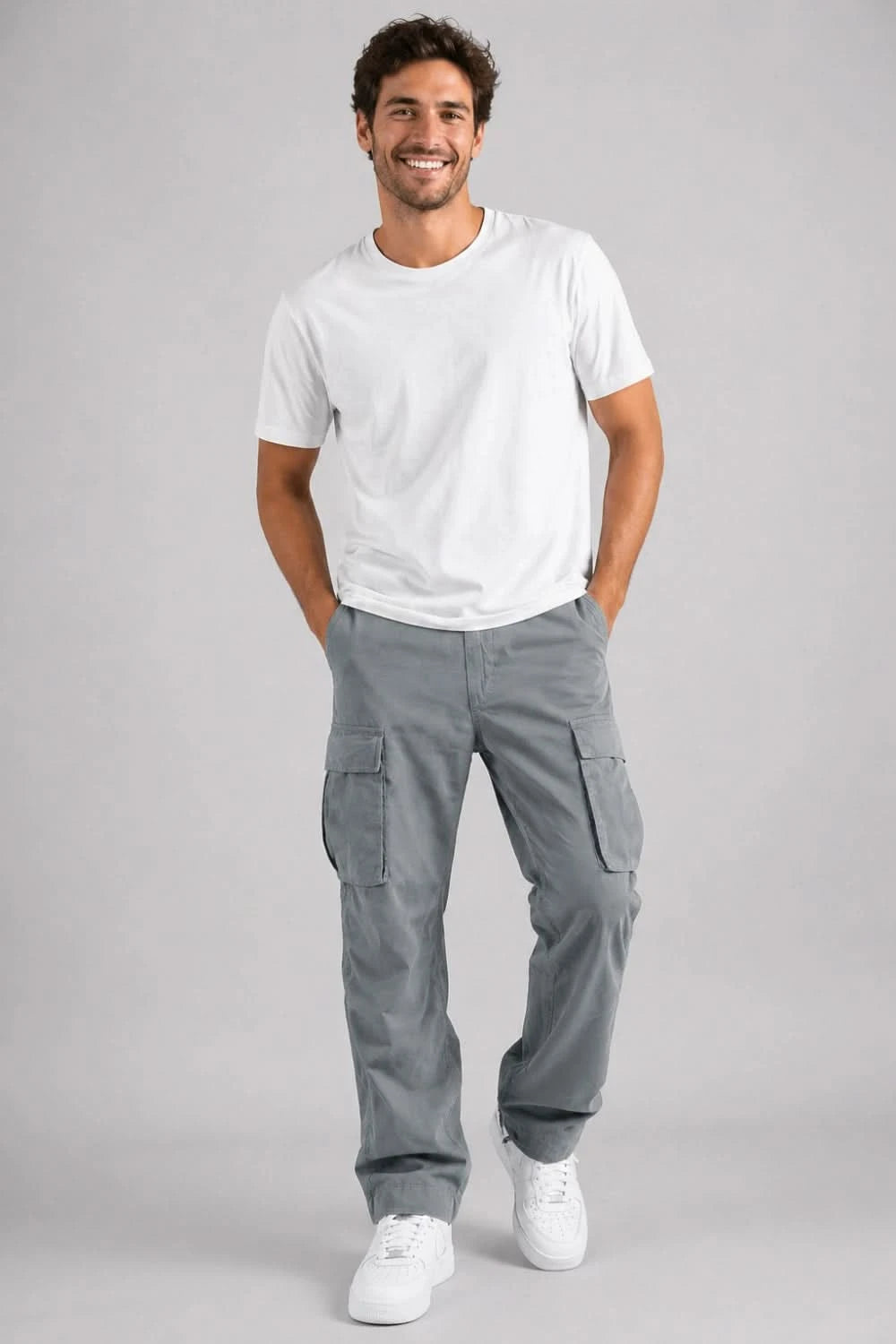 Man wearing a white t-shirt and gray cargo pants on a gray background