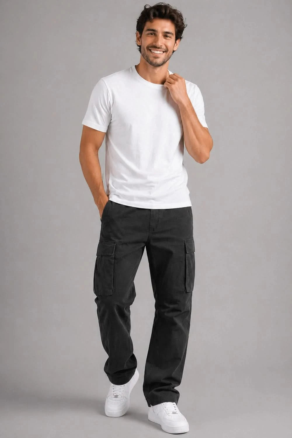 Man wearing a white t-shirt and black cargo pants on a gray background