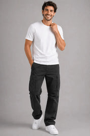 Man wearing a white t-shirt and black cargo pants on a gray background