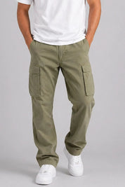 Person wearing olive green cargo pants and white sneakers on a gray background