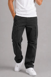 Person wearing black cargo pants and white sneakers on a gray background