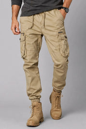 Person wearing beige cargo pants and tan boots on a gray background