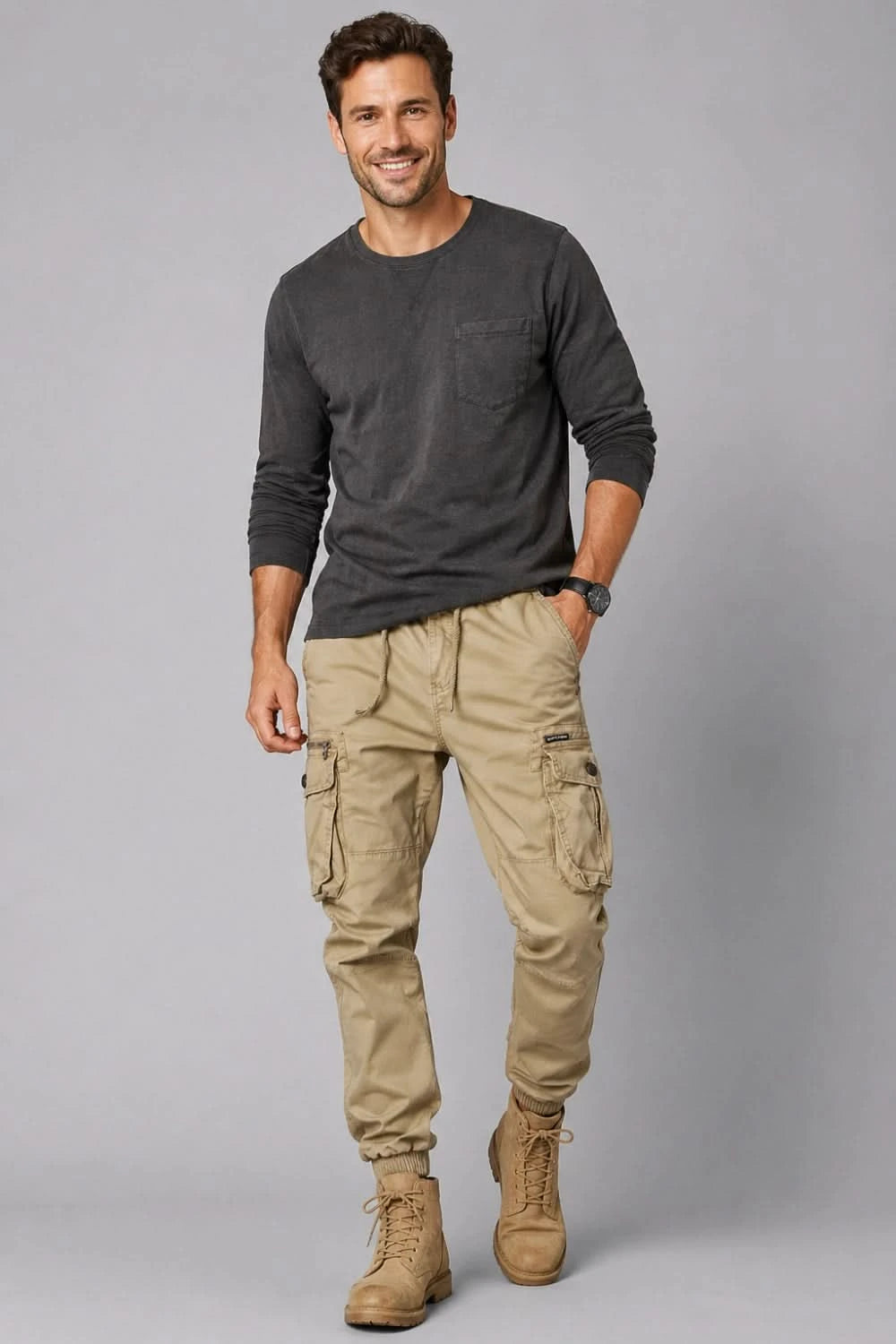 Man wearing a dark long-sleeve shirt and beige cargo pants on a gray background