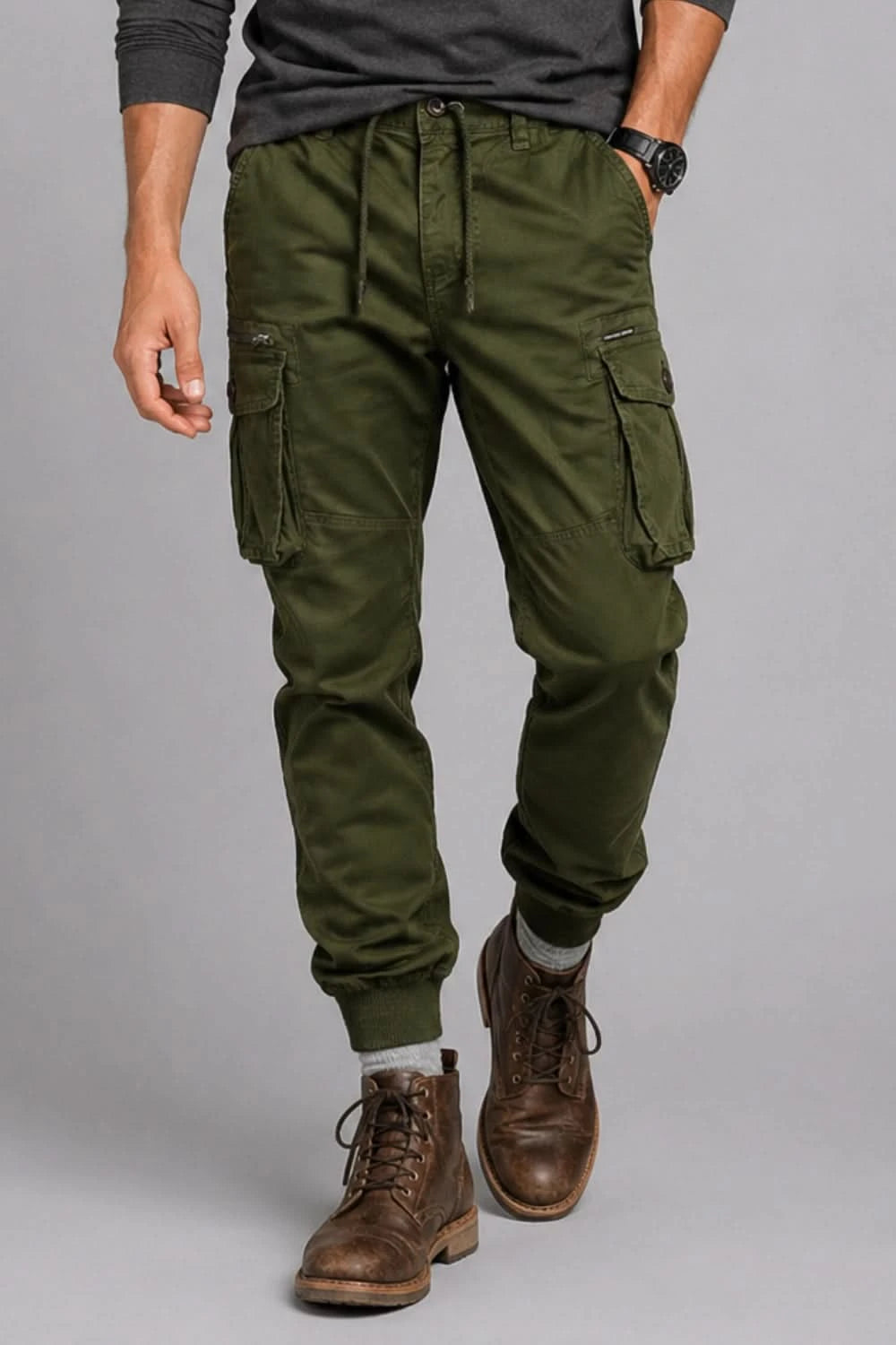 Person wearing green cargo pants and brown boots on a gray background