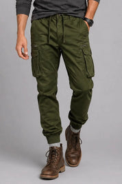 Person wearing green cargo pants and brown boots on a gray background