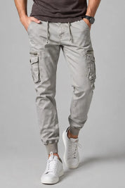 Person wearing light gray cargo pants and white sneakers on a gray background