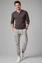 Man wearing a brown long-sleeve shirt and gray cargo pants on a gray background