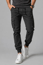 Person wearing black cargo pants and white sneakers on a gray background